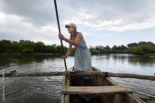 A tourist girl is rowing an old boat on the Congo River in Africa. view of woman paddling wooden canoe. Canoe girl paddling wooden boat
