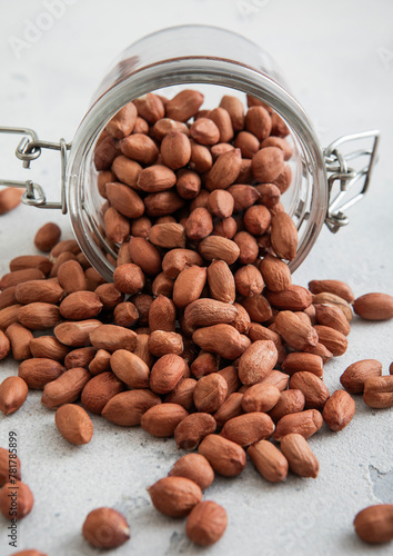 Raw healthy red peanut nuts in glass jar on white kitchen table.Macro.