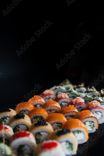 rolls beautifully decorated with lemon caviar on a dark background