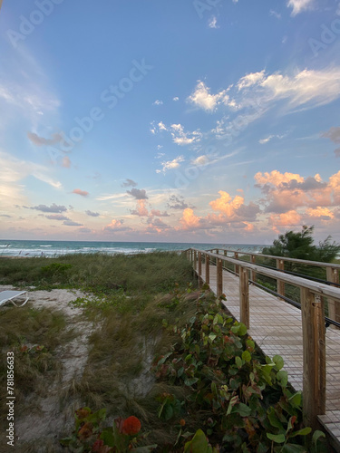 Boardwalk into Florida beach at sunset with cloudy sky