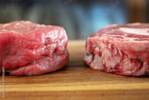 detail of filet mignon and ribeye side by side on wood cutting board