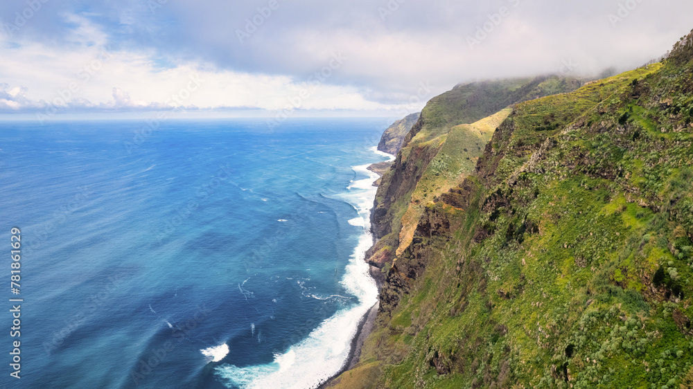 Breathtaking Madeira panorama - powerful cliffs, surging sea, foamy cascades, and lazy clouds. The contrast of raw nature with the blue sky amazes nature lovers