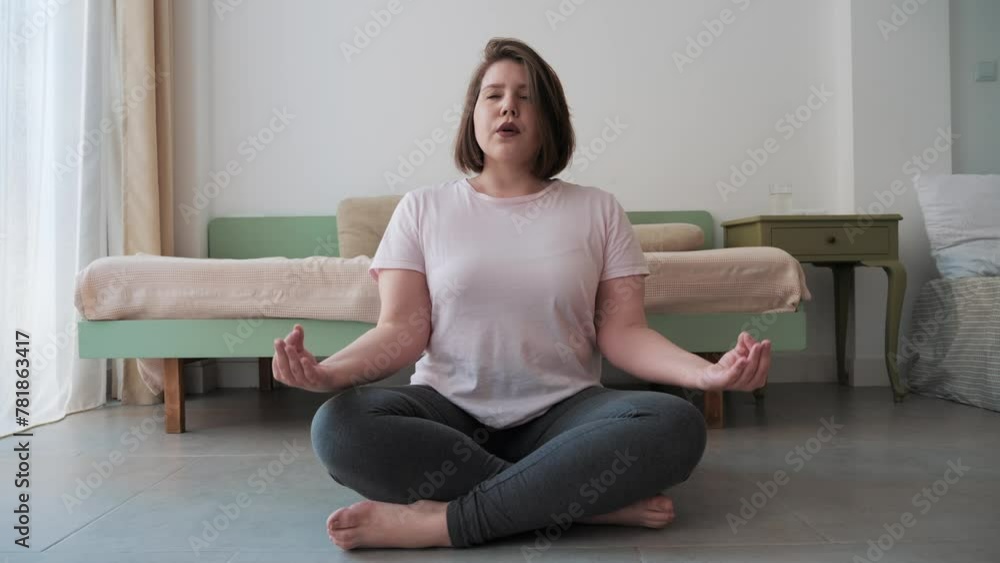 Woman sits cross legged on floor, deeply engaged in breathing exercise for relaxation and health. Woman sits cross legged on floor, deeply engaged in breathing exercise for relaxation and health.