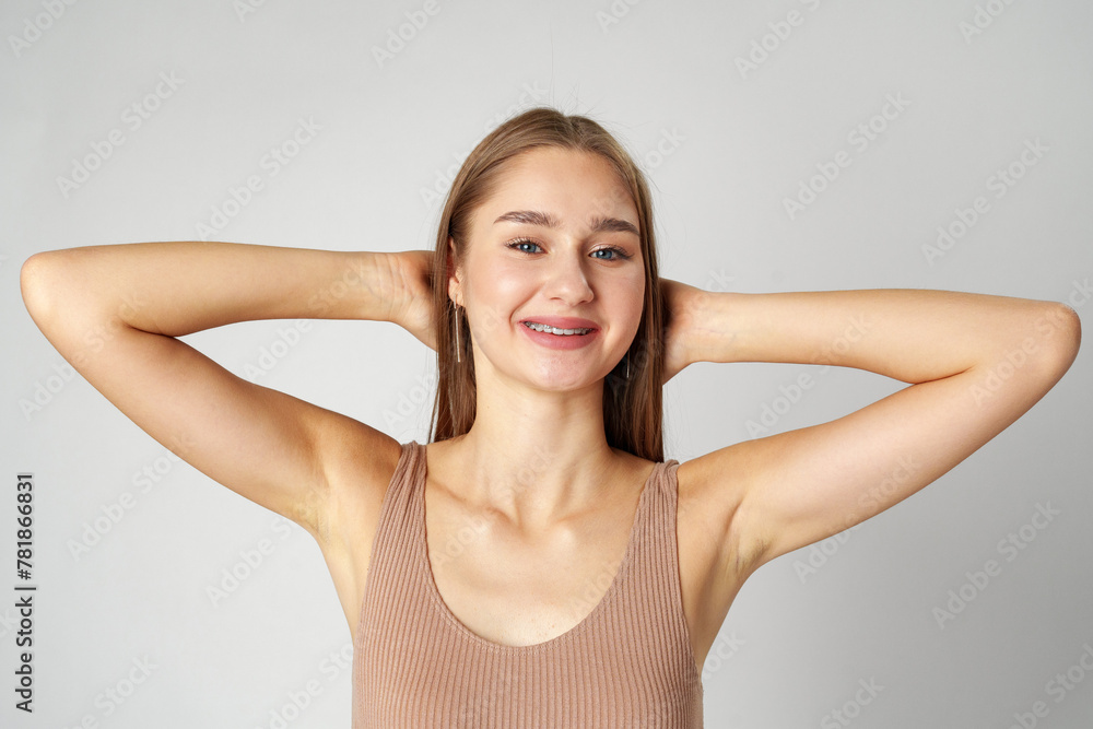 Smiling young woman posing to camera over gray background in studio Smiling young woman posing to camera over gray background in studio
