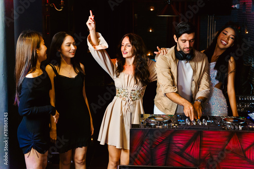 Group of energetic women dancing friends with DJ enjoying night party. Young women dance in the nightclub. Nightlife, disco dance and girl's night party concept. Fun music festival