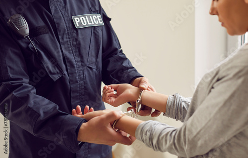 Close up view of a policeman putting handcuffs on a suspect woman. The arrest is being made as part of police procedures related to a criminal crime, with the woman taken into custody under the law. photo
