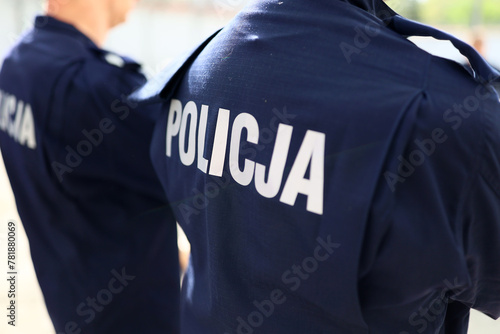 Napis policja na niebieskim mundurze. © FotoDax