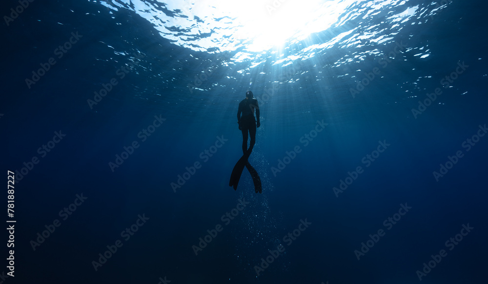 Naklejka premium Freediver Swimming in Deep Sea With Sunrays.