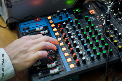 Sound engineer manipulating knobs on mixing console for audio mixing at event
