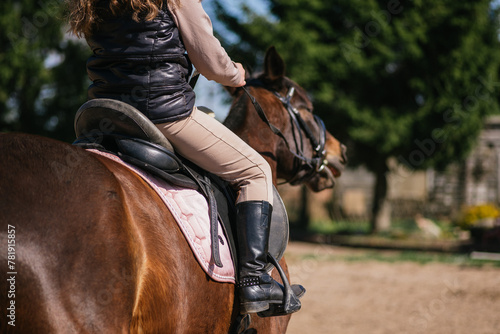 Girl practicing on horseback, riding training boots and horse saddle visible