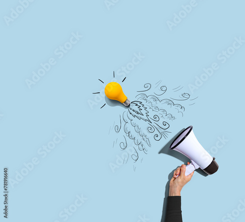 Attention and announcement concept with an idea light bulb flying to the sky like a rocket - Flat lay