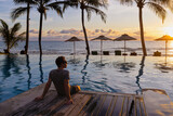 man relaxing near swimming pool in luxurious hotel resort at sunset, beach vacation travel