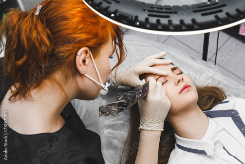 A cosmetologist applies permanent makeup to the eyebrows - eyebrow tattoo. eyebrow perm photo