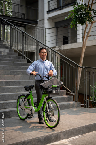 A happy, carefree Asian businessman going to work with his bicycle on a sunny day.