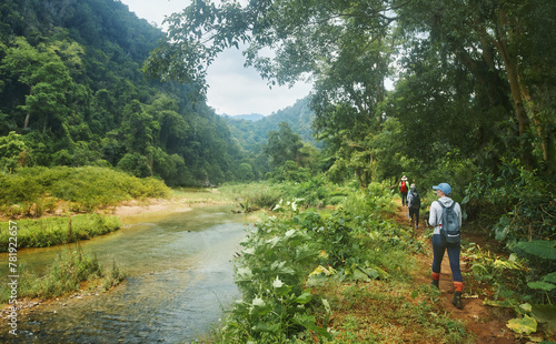 Group of hikers in jungle walk along path along river to famous Phong Nha Caves in Vietnam. © soft_light