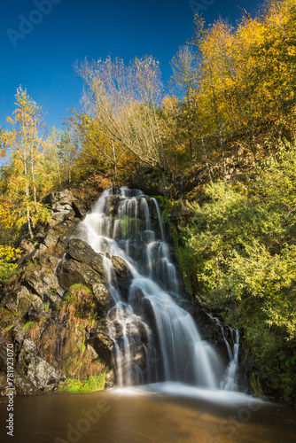 Early autumn colors on a sunny day at the 9 meter high waterfall in the village of Masty