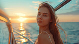 Young beautiful slender woman in a dress on the deck of a luxury yacht on the open sea against the backdrop of sunset