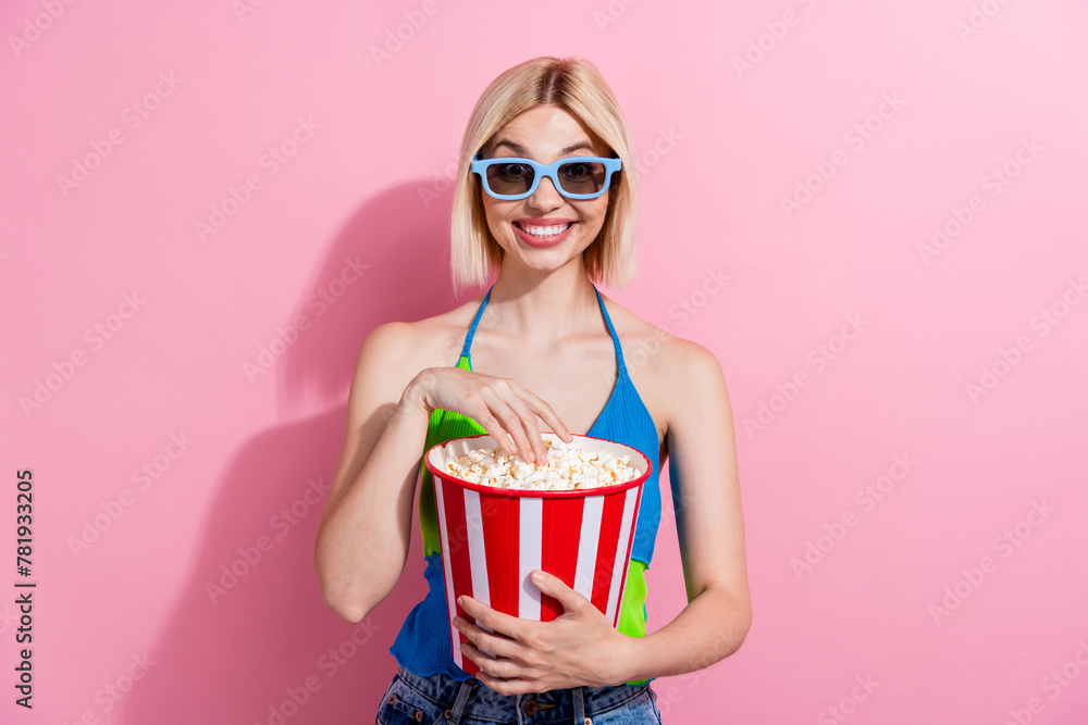 Portrait of satisfied woman with bob hairstyle wear colorful top in 3d glasses eat popcorn at cinema isolated on pink color background