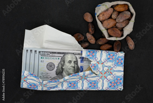 United States Dollars or American Dollars as the chocolate bar. Cocoa bean. Black background. The price of cocoa beans. Jump prices of chocolate.