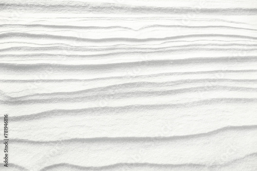 Surface of the earth covered with white snow, with an abstract pattern in the form of waves formed by the action of the wind