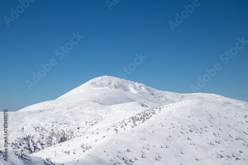 minimalistic winter mountain landscape, snowy mountain range on blue sky background © Jeannie 