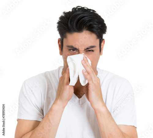 Closeup portrait of sick young man with allergy or germs cold, blowing his nose looking miserable unwell very sick, isolated on white background.