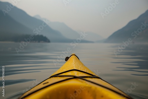 A closeup shot of the front tip of an open yellow kayak on calm waters, with mountains in misty background, smoke from forest fires creating hazy atmosphere, stunning natural color © Svetlana