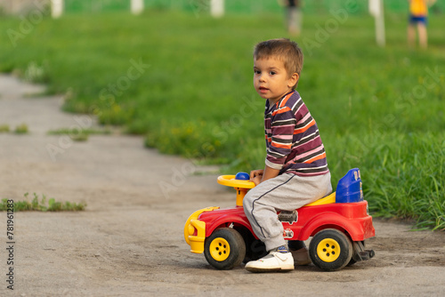 boy in a denim jacket sitting on a toy car, family and sports, toy car, spring, walk, family sport, study