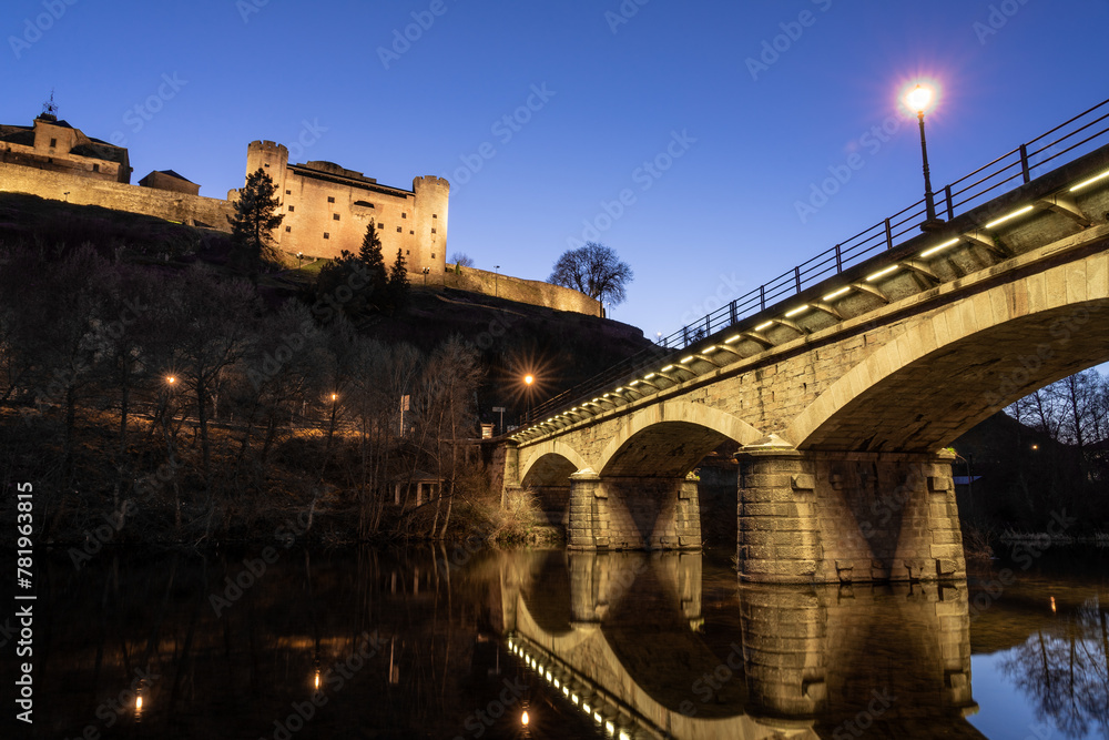 Castle and bridge illuminated at night of the medieval village of Puebla de Sanabria reflected on the Tera river, Zamora, Castilla y Leon, Spain