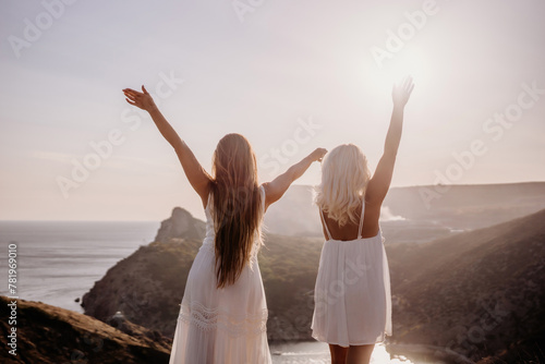 Two women are standing on a hill overlooking the ocean. They are holding hands and looking out at the water. The scene is peaceful and serene, with the sun shining brightly in the background.