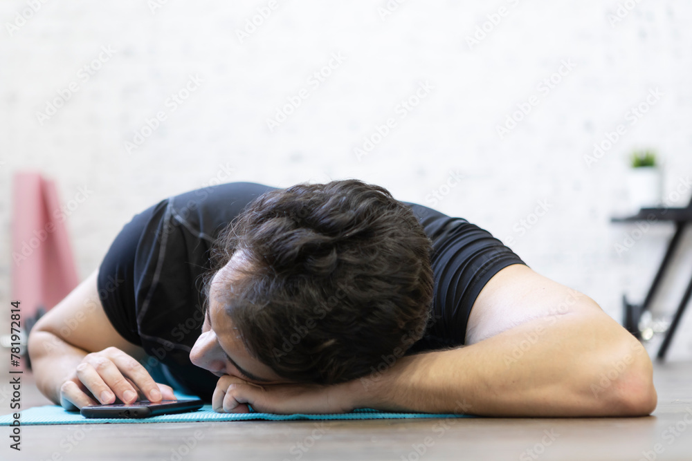 Tired young man yawning while training on the floor at home. Do sport and exercise at the morning time concept Tired young man yawning while training on the floor at home. Do sport and exercise at the morning time concept