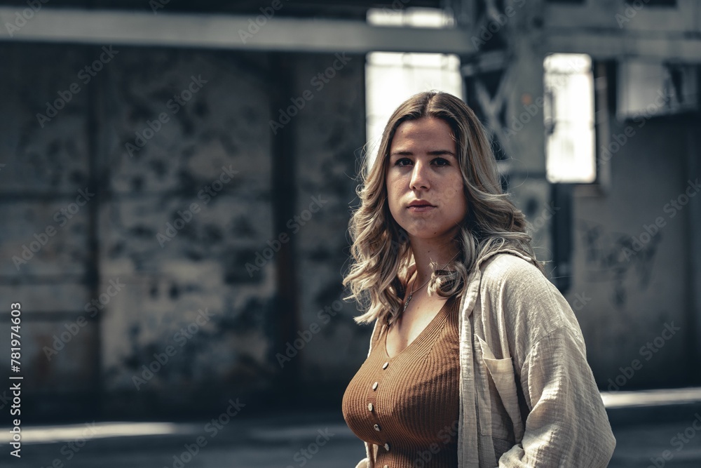 Closeup of a female standing indoors in an empty building and looking at the camera