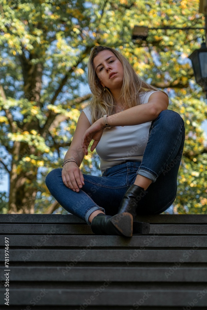 Vertical closeup of a young blonde woman sitting on the stairs and looking at the camera. Vertical closeup of a young blonde woman sitting on the stairs and looking at the camera.