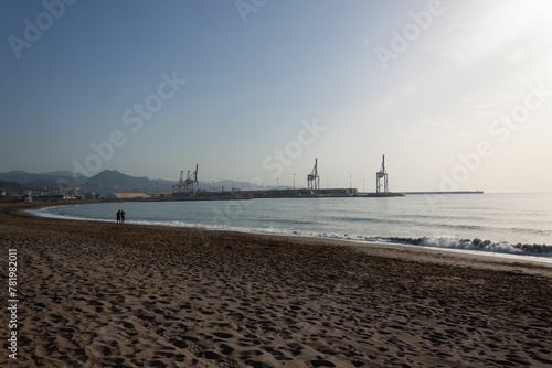 Sandy beach in Malaga with industrial port on the background