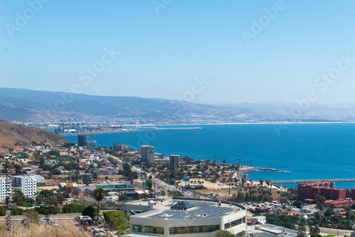 Aerial shot of a city in front of the blue sea.