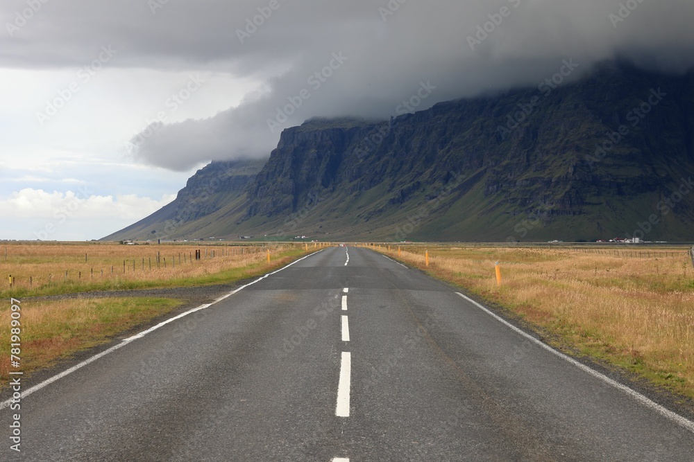 Beautiful view of a road with dry fields and mountains under the cloudy sky
