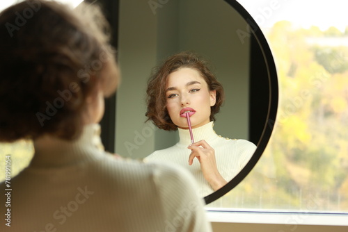 Принти на полотні young woman looking in a mirror applying make up