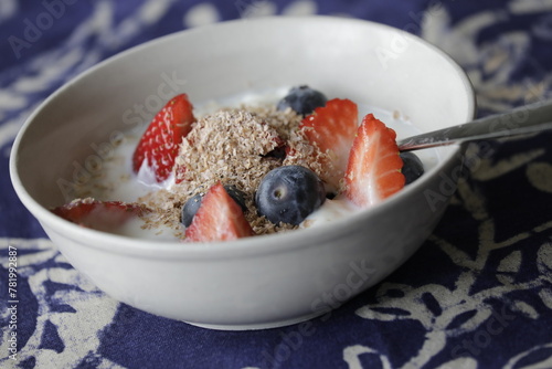 Healthy breakfast, muesli bowl with oat flakes, wheat bran, strawberries, blueberries and yogurt, low carb close up.