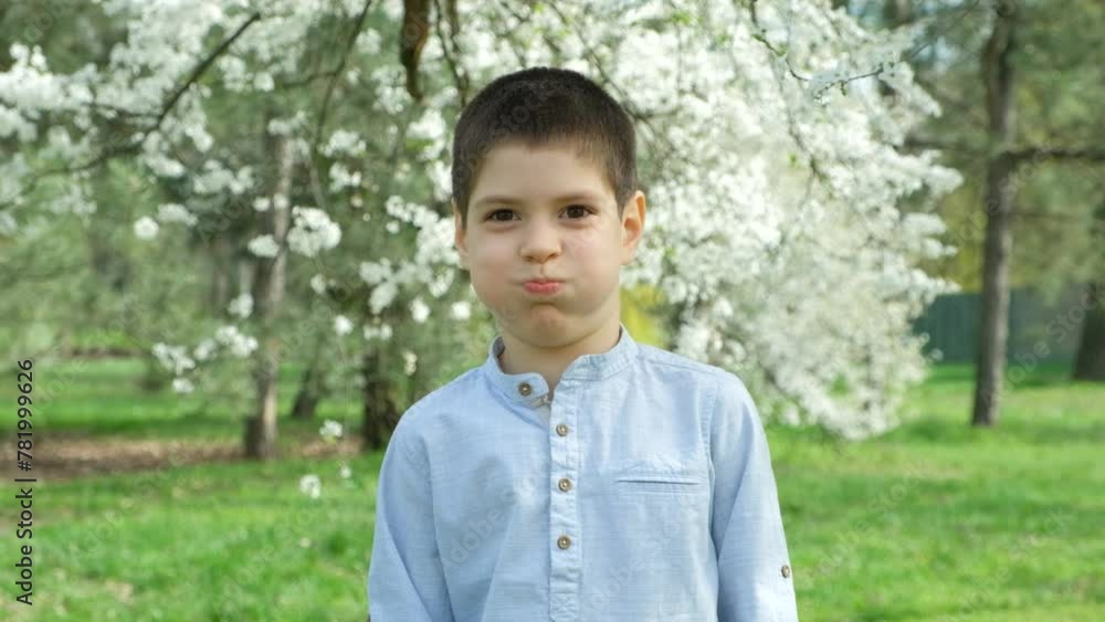 Cute six-year-old boy fooling around and grimacing, puffing out his cheeks.