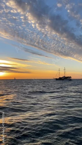 View from the deck of a passing ship during a boat trip, waves during a cruise, against the background of an evening sunset in the sky.