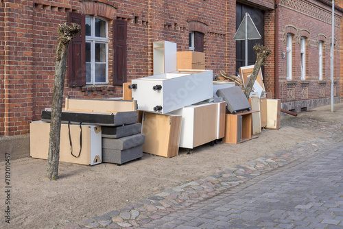 Pile of bulky waste with furniture on the side of the road in front of a house