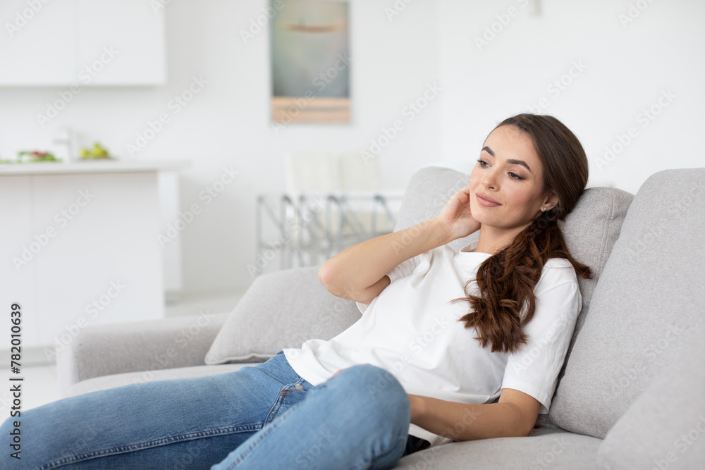Beautiful smiling authentic woman look at camera, sitting on couch in living room at home. Beautiful smiling authentic woman look at camera, sitting on couch in living room at home.