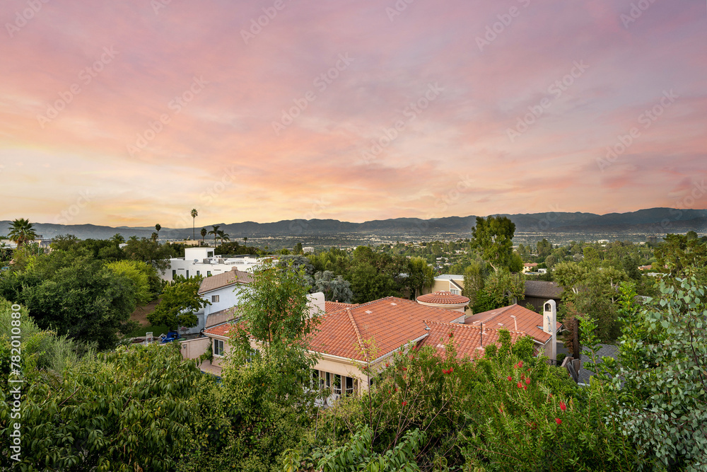 Sunset view behind a spacious house and trees in Encino, California