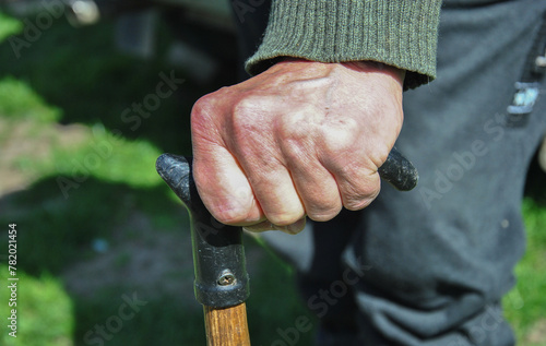 the hand of an elderly man leans on a walking cane close-up. blurred background.