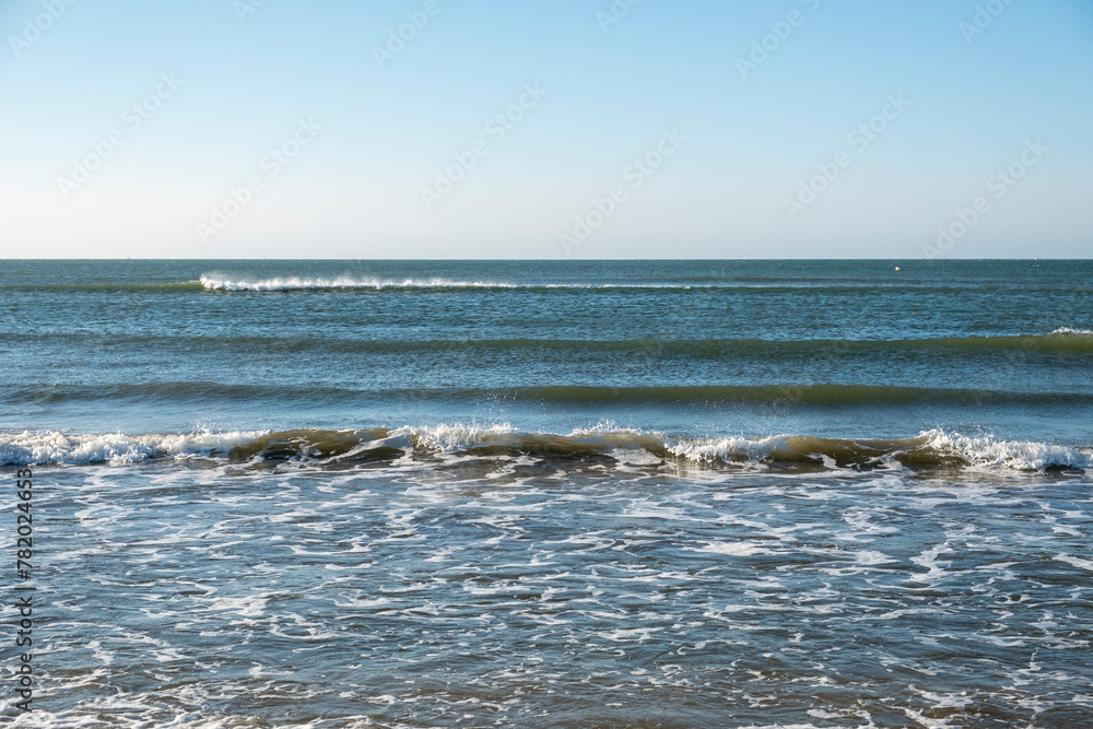 Fototapeta premium Detail of the waves of the Atlantic sea beating on the golden sand beach during the summer holidays in the province of Huelva, Spain.