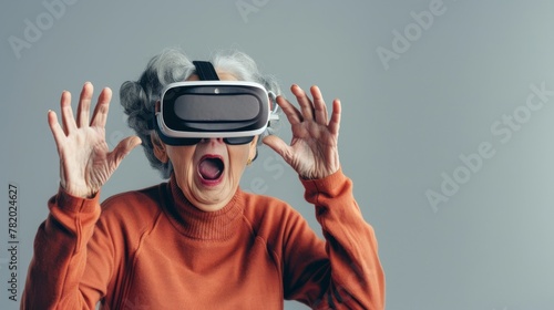 Seniors and technology, entertainment. A portrait of an elderly woman or grandmother in VR (virtual reality) glasses, with surprised hand gestures.
