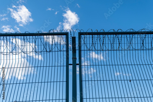 Concertina barb wire, heavy duty, metal fence. A prison, crime concept low angle shot. Horizontal, real photo.