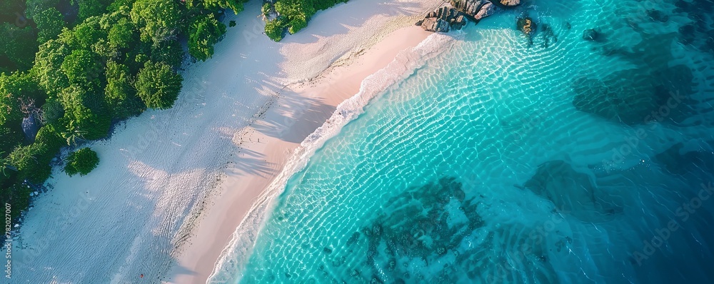 Drone view of a pristine beach with turquoise waters and white sand, conveying a sense of paradise and relaxation.