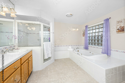 Stylish bathroom with purple curtains  sink  and spacious white bathtub in Encino  CA