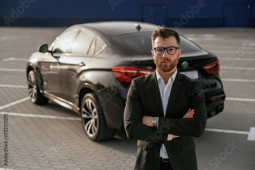 Wallpaper Mural Standing with arms crossed. Businessman in suit is near his black car outdoors Torontodigital.ca